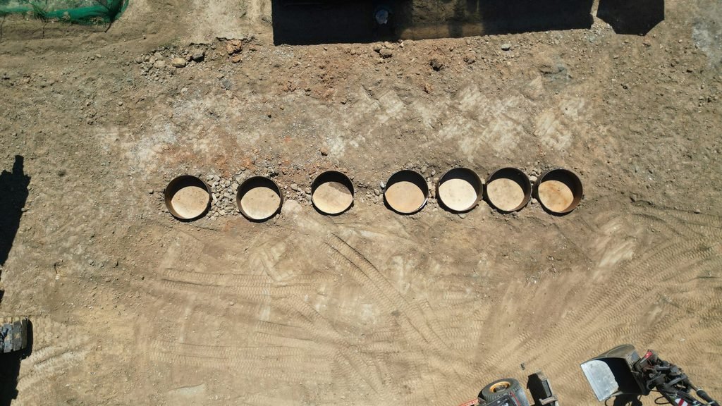 Seven UHPC test cylinders buried flush with the ground, drone top-down view